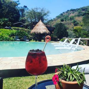 a drink sitting on a table next to a pool at Pousada do Coura in Pouso Alto