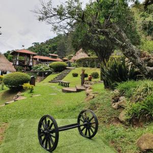a garden with a wagon wheel in the grass at Pousada do Coura in Pouso Alto