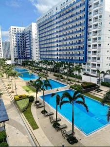 a large hotel with a large pool and palm trees at Mall of Asia Condotel Pasay Philippines in Manila