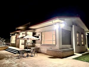 a house with a table and chairs and an umbrella at redhouse in Puli