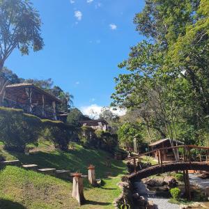 a wooden bridge over a stream in a park at Pousada do Coura in Pouso Alto