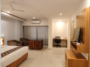 a hotel room with a bed and a desk and a television at Hotel Indriya Wayanad in Kalpetta