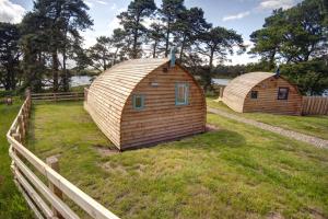 two wooden huts in a field next to a fence at Finest Retreats - The Wonneys Glamping in Hexham