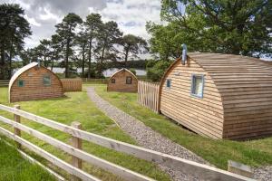 three wooden huts in a field next to a fence at Finest Retreats - Wheatleys Glamping in Hexham