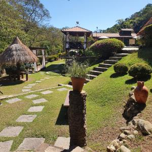 a garden with a stone pillar with a vase on it at Pousada do Coura in Pouso Alto