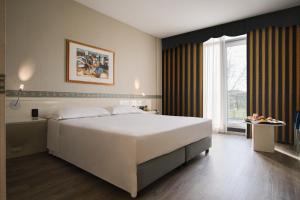 una camera da letto con un grande letto bianco e una finestra di Hotel Viest a Vicenza