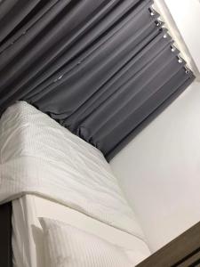 a bed with white sheets and a black curtain at Mall of Asia Condotel Pasay Philippines in Manila