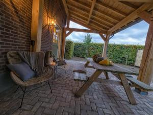 een patio met een houten picknicktafel en stoelen bij Gastenverblijf Bie Zus in Buggenum