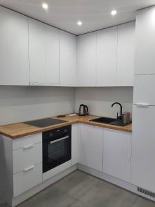 a white kitchen with white cabinets and a sink at Welcome Apartment in Suwałki