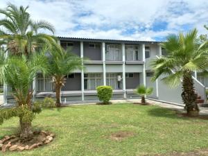 a building with palm trees in front of it at Crescent Lodge in Livingstone