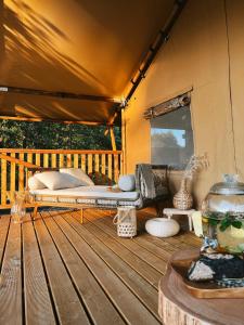 une tente avec un lit sur une terrasse en bois dans l'établissement Freedolina Glamping, à Łowyń