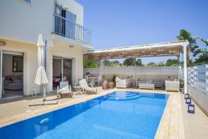 a house with a swimming pool and a patio at Villa Posidonas Three in Protaras