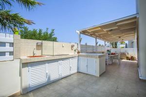 an outdoor kitchen with a sink and a patio at Villa Posidonas Three in Protaras