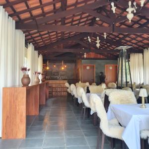 a dining room with white tables and white chairs at Pousada do Coura in Pouso Alto