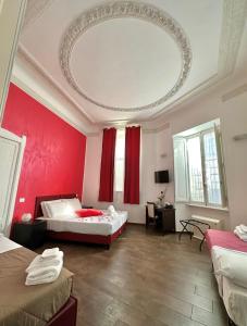 ローマにあるイル テンピオ デッラ キャピタルの赤い壁の客室で、ベッド2台が備わります。