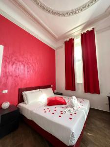 ローマにあるイル テンピオ デッラ キャピタルの赤い壁のベッドルーム1室、赤いカーテン付きのベッド1台が備わります。