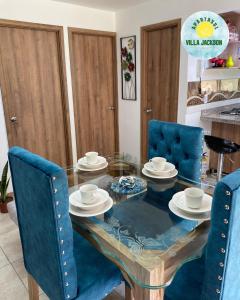 a dining room with a glass table and blue chairs at Villa Jackson in La Tebaida