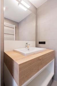 La salle de bains est pourvue d'un lavabo blanc et d'un miroir. dans l'établissement Belcasa Mar Suites & Lofts, à Middelkerke