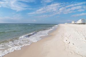 a sandy beach with the ocean and buildings in the background at The Dunes 704 in Gulf Shores