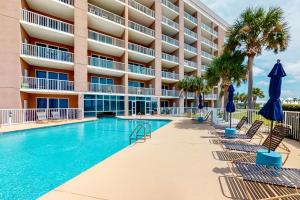 a pool with chairs and umbrellas in front of a hotel at The Dunes 704 in Gulf Shores