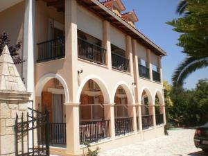 a large white building with balconies and a palm tree at Loukas Inn Family Resort in Keri