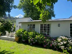 een wit huis met een tuin met bloemen bij Lakeside Cottage on Spring Grove in Nottingham Road