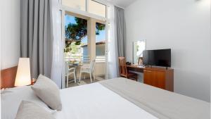 a bedroom with a bed and a desk and a television at Hotel Vis in Dubrovnik