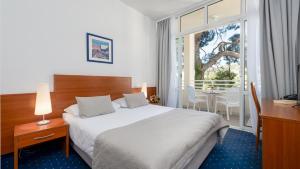 a hotel room with a bed and a desk and a window at Hotel Vis in Dubrovnik