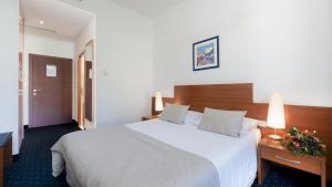 a hotel room with a large bed and flowers on a table at Hotel Vis in Dubrovnik