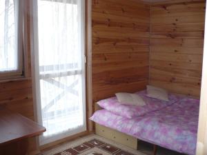 um pequeno quarto com uma cama numa parede de madeira em Kryjówka Ichuna em Werlas