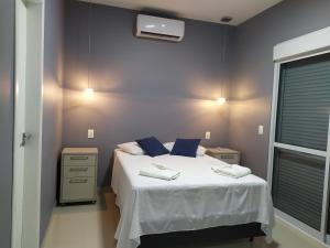 a bedroom with a white bed with blue pillows at Casa Excepcional na Praia Brava - Florianópolis in Florianópolis
