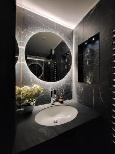 La salle de bains est pourvue d'un lavabo et d'un miroir rond. dans l'établissement E. D. Elite Apartment, à Šiauliai