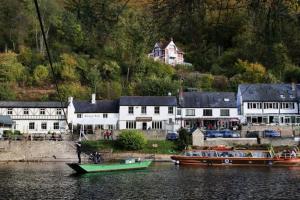 dos barcos están atracados en el agua junto a las casas en The Chaff House Country Cottage en Welsh Newton Common