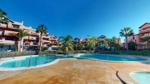 una piscina en un complejo con palmeras y edificios en Casa Abeto A - Murcia Holiday Rentals Property, en Torre-Pacheco
