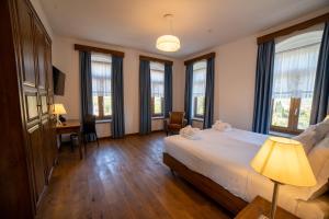 a bedroom with a bed and a desk and windows at VILLA PERMET in Përmet