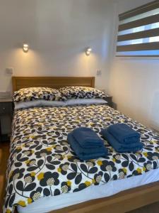 a bed with two blue pillows on top of it at The View. Stylish modern Chalet in great location. in Cromer