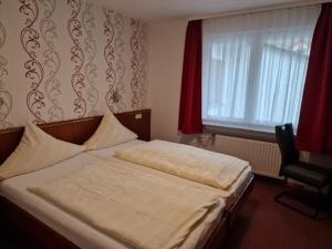 a bedroom with a bed and a window with red curtains at Hotel Weinhaus Am Stiftstor in Treis-Karden