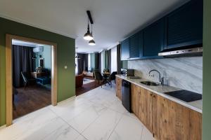 a kitchen with blue cabinets and a living room at Avenue Hotel - Free Parking in Sofia
