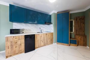 a kitchen with blue cabinets and a black dishwasher at Avenue Hotel - Free Parking in Sofia