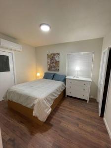 a bedroom with a bed and a dresser with a lamp at Brand New 2BR CUTE Blue LED in North Fresno in Fresno