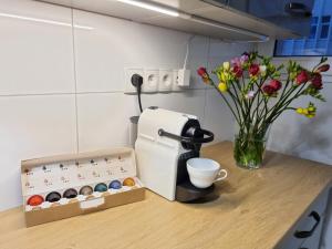 uma mesa com comodidades para preparar café e um vaso de flores em My Beloved Warsaw em Varsóvia