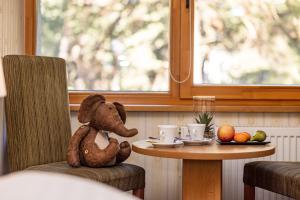 um urso de peluche sentado numa cadeira ao lado de uma mesa em Palanga Park Hotel em Palanga