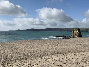 uma praia arenosa com uma grande rocha na água em The Duke of Cornwall em St Austell