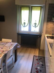 a dining room with a table and two windows at "La Bella della Cappuccina" Casa con Parcheggio Interno Gratuito in Domodossola