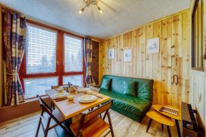 uma sala de jantar com uma mesa e um sofá verde em Apollo em Le Corbier