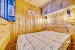 um quarto com uma cama num quarto de madeira em Apollo em Le Corbier
