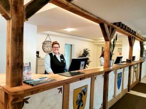 Eine Frau, die hinter einem Tresen in einem Laden steht. in der Unterkunft Hasseröder Burghotel in Wernigerode