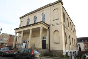 a building with two cars parked in front of it at Wesley House in Cheltenham