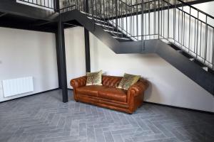 a brown leather couch sitting under a staircase at Wesley House in Cheltenham