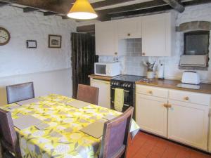 cocina con mesa y mantel blanco y amarillo en Oxlow End Cottage, en Peak Forest